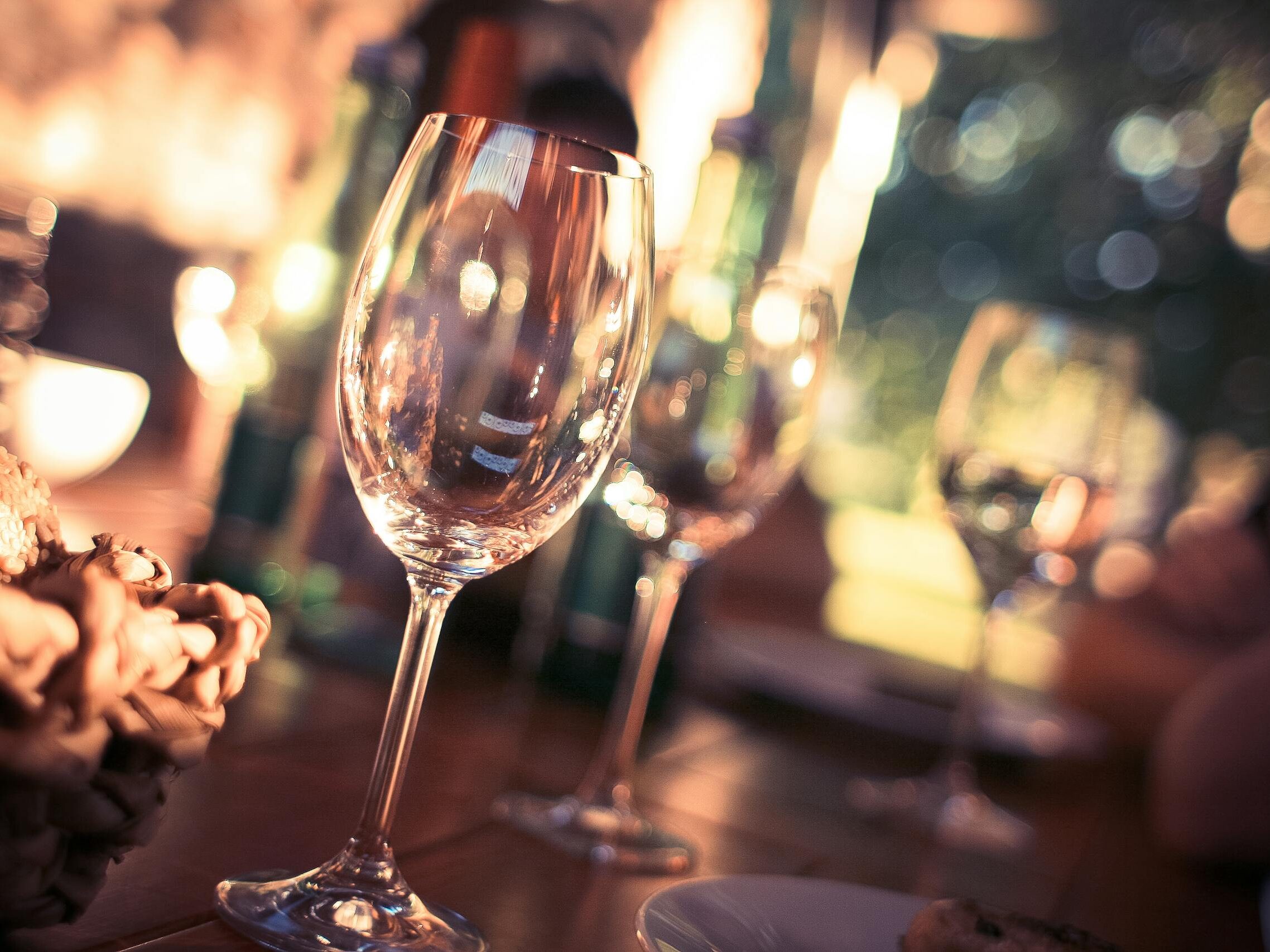 Close-up of wine glasses on a dining table with bokeh lights, creating a warm and inviting atmosphere.